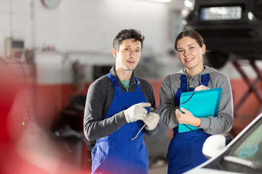 Car service manager discusses car repair problems with a mechanic. He takes notes on paper - Powered by Adobe