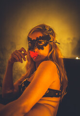 sensual woman in lace mask posing in intimate boudoir setting