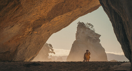 Traveler in cave at Cathedral Cove, New Zealand at sunrise