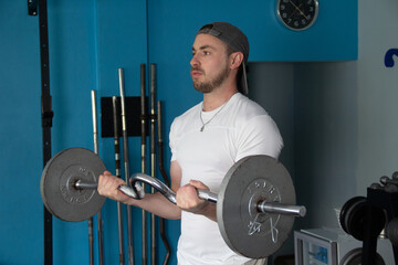 Male athlete performing bicep curls with barbell in gym