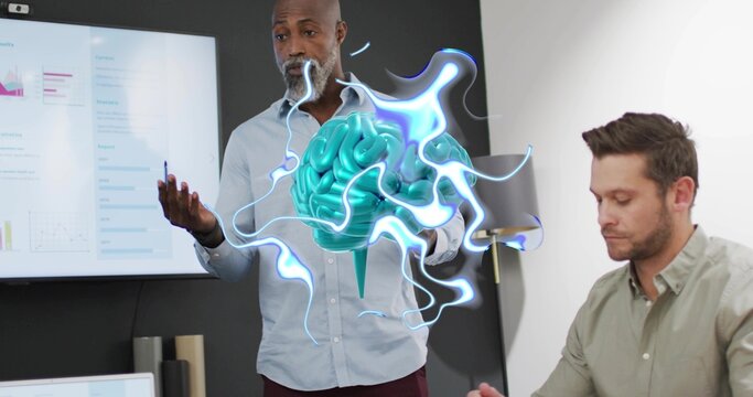 Gesturing man in button-up shirt presenting 3D brain hologram in meeting room, with display screen