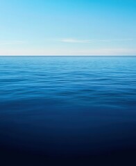 Obraz premium Calm deep blue ocean showing horizon line under a clear light blue sky. Tranquil seascape background with copy space