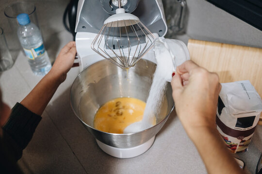 Woman adding sugar to eggs preparing cake batter