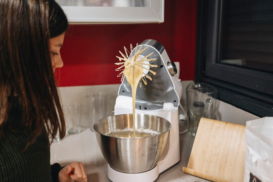 Girl baking cake in kitchen using stand mixer