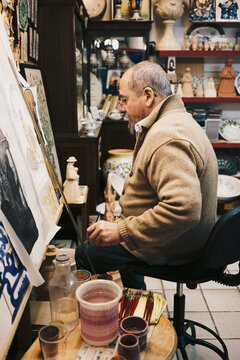 Andalusian ceramic craftsman painting traditional tiles in workshop