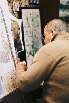 Andalusian craftsman painting traditional ceramic tiles in workshop