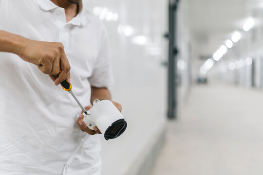 Unrecognizable man fixing security cam with tool