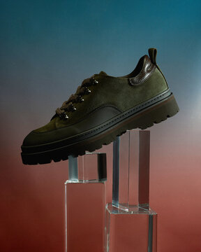 Stylish green sneakers displayed on a clear pedestal
