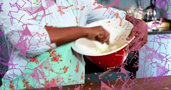 Home cook dipping whisk into batter and stirring for smooth batter with drifting pink orange shapes
