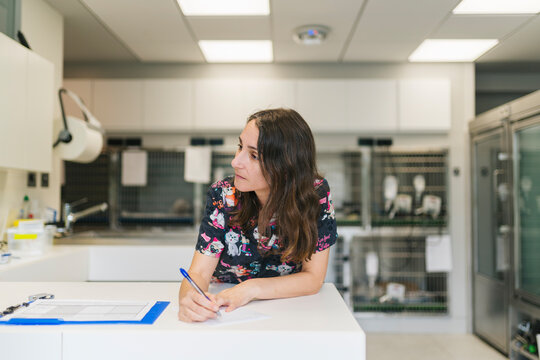Veterinarian writing notes on clipboard in veterinary clinic