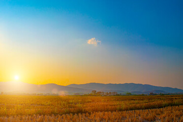 Happy holiday and relax with view of Sunset in a field and mountains in countryside. Beautiful Natural Landscape.Sunlight in the colorful fields,