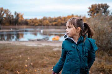 Girl watching nature with binoculars in autumn park