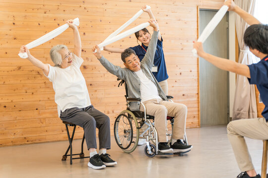 Senior men and women doing exercises and stretching at a nursing home, day care center, and staff
