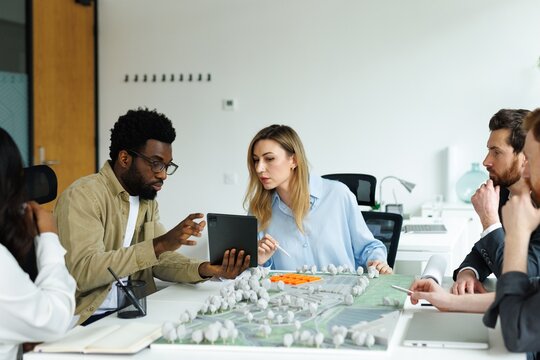 Black male architect showing something on laptop to female colleague