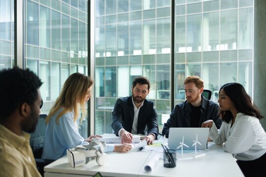 Male company boss showing something on blueprint to architects