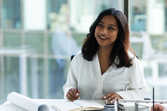 Smiling female architect listening unknown colleague during meeting