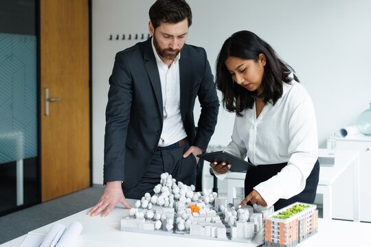 Adult male company boss listening young female architect with tablet