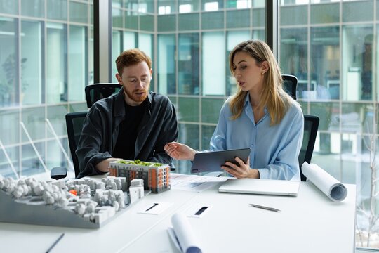 Female architect showing on tablet to concentrated male colleague