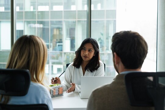 Back cropped view of couple clients looking at real estate agent