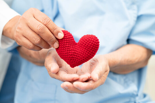 Asian elder senior woman patient holding red heart in hospital.