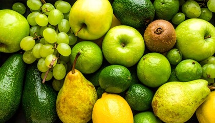 Vibrant green and yellow fruit flat lay background. Fresh organic mix of apples, pears, grapes, avocado, and kiwi for healthy detox diet concepts.