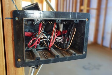 Black electrical light switch and wiring attached to stud
