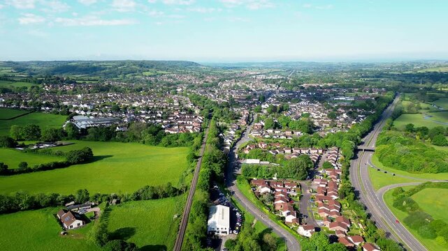 Wide angle aerial drone footage of Honiton in Devon, UK flying west showing the railway