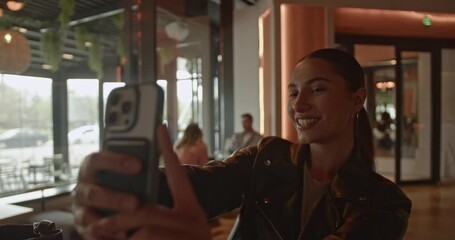 A confident young businesswoman in a contemporary lounge setting uses her smartphone for seamless digital communication. Her engagement highlights the ease of connectivity in modern professional life. - Powered by Adobe