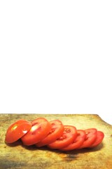 Fresh red tomato slices, solanum lycopersicum or lycopersicum esculentum on an old wooden cutting board photographed on the isolated white background