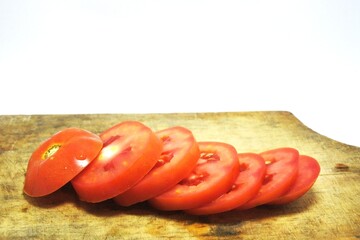 Fresh red tomato slices, solanum lycopersicum or lycopersicum esculentum on an old wooden cutting board photographed on the isolated white background