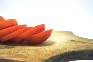 Fresh red tomato slices, solanum lycopersicum or lycopersicum esculentum on an old wooden cutting board photographed on the isolated white background