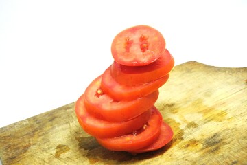 Fresh red tomato slices, solanum lycopersicum or lycopersicum esculentum on an old wooden cutting board photographed on the isolated white background