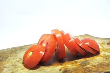 Fresh red tomato slices, solanum lycopersicum or lycopersicum esculentum on an old wooden cutting board photographed on the isolated white background