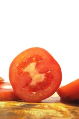 Fresh red tomato slices, solanum lycopersicum or lycopersicum esculentum on an old wooden cutting board photographed on the isolated white background