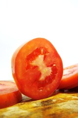 Fresh red tomato slices, solanum lycopersicum or lycopersicum esculentum on an old wooden cutting board photographed on the isolated white background
