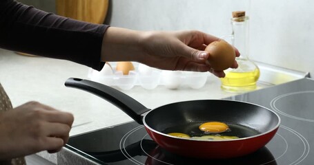 Woman cracking egg into frying pan in kitchen, closeup - Powered by Adobe