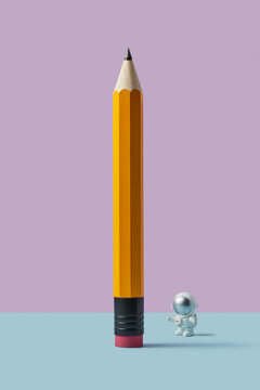 Astronaut toy beside giant yellow pencil