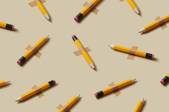 Repeated yellow pencils taped on beige background