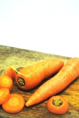 The fresh orange carrots or daucus carota on an old wooden chopping board