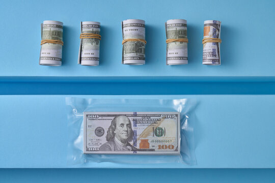 Rolled bills and sealed dollar stack on blue