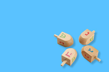 Hanukkah, four dreidels with Hebrew letters displayed on blue