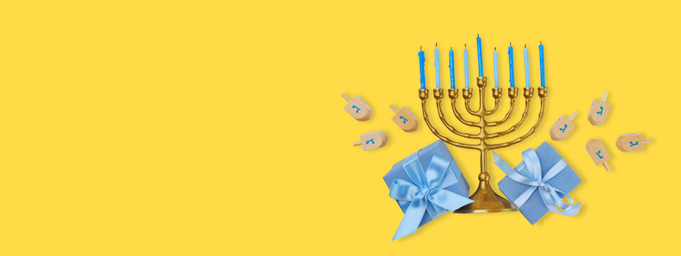 Decorative menorah with blue candles and gifts near dreidels
