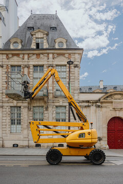 Yellow construction lift in front of historic building