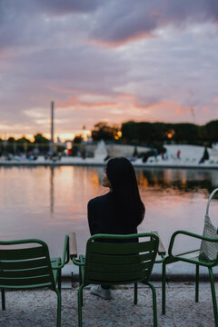 Woman sitting by pond at sunset