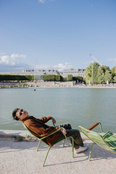 Man Relaxes by the Water in a Park During a Sunny Day