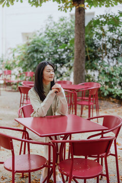 Woman sitting at red outdoor caf&eacute; table