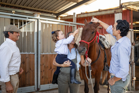 generational family caring for a horse in stables