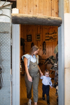 Pregnant mother and daughter leaving a stable with horse equipment