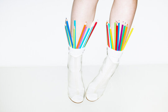 Person wearing socks and heels filled with colourful office pencils