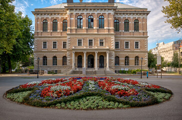 Zagreb, Croatia – July 18, 2025: The Croatian Academy of Sciences and Arts (HAZU) stands behind a circular floral display in Zrinjevac Park.  © Torval Mork